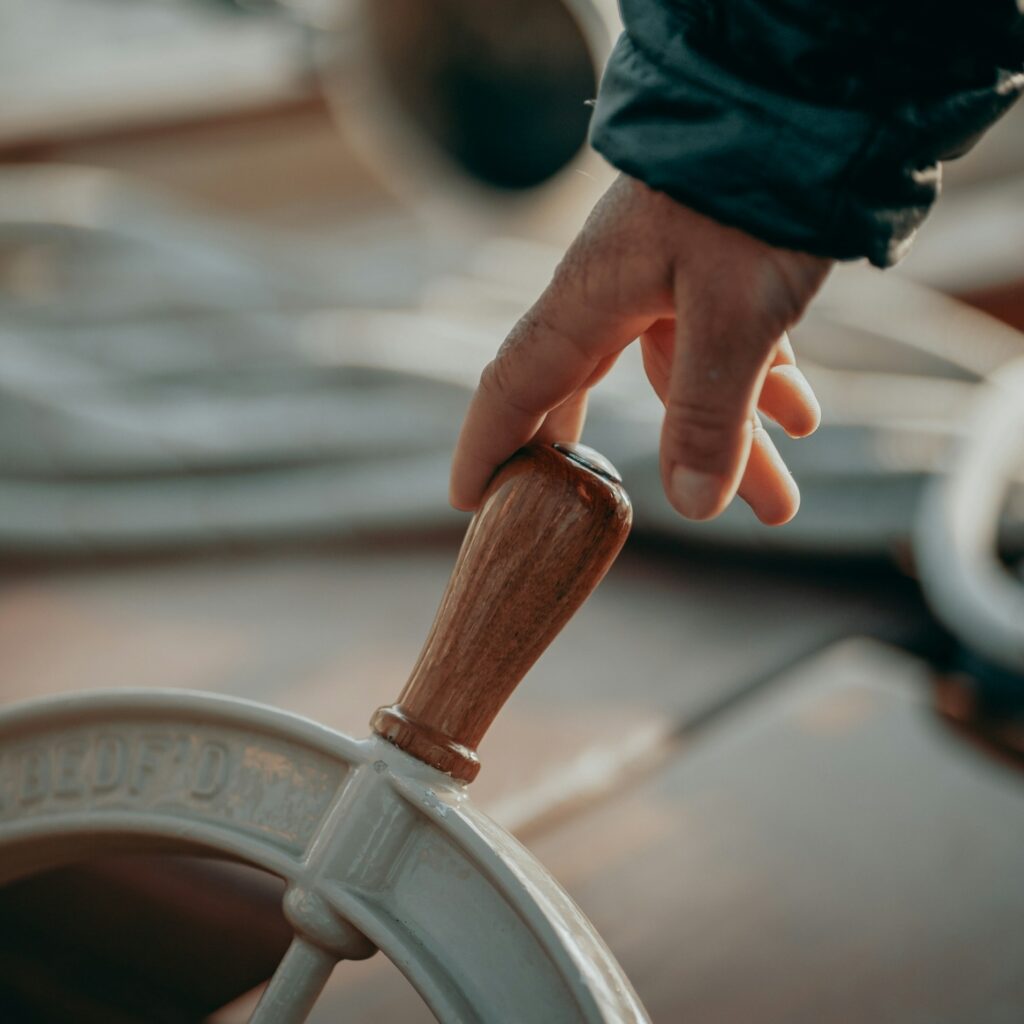 Person holding a ship's steering wheel with one finger